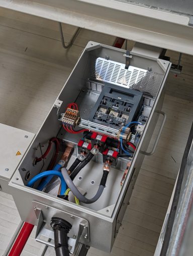 Verteilungsbox mit Kabeln, Sicherungen und elektrischen Anschlüssen.